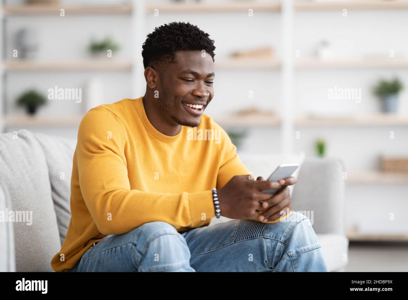 Handsome black guy chatting with girlfriend, using cellphone at home Stock Photo