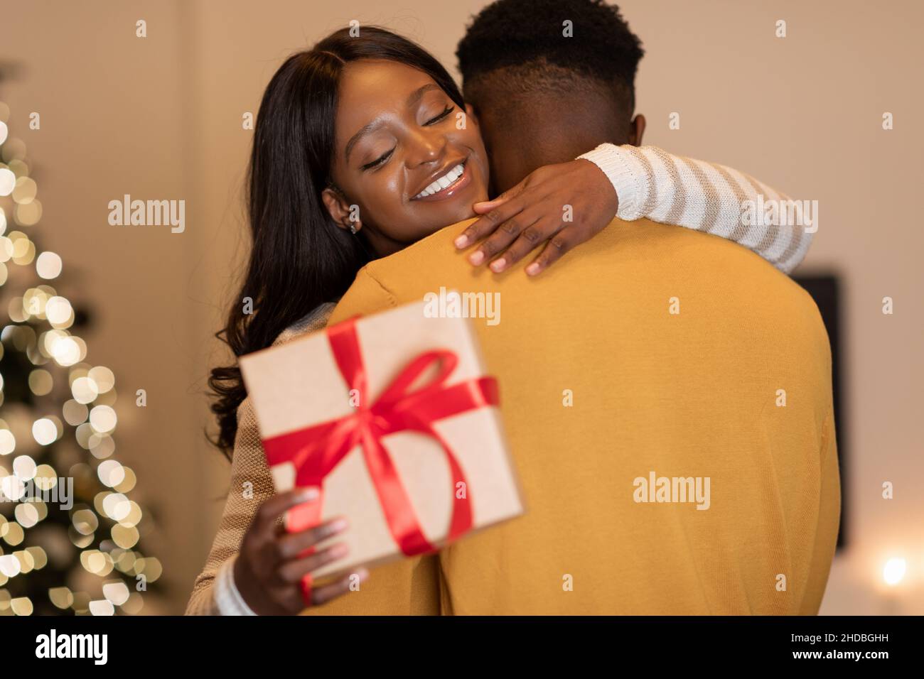 African American Wife Hugging Husband Holding Gift Celebrating Holiday ...