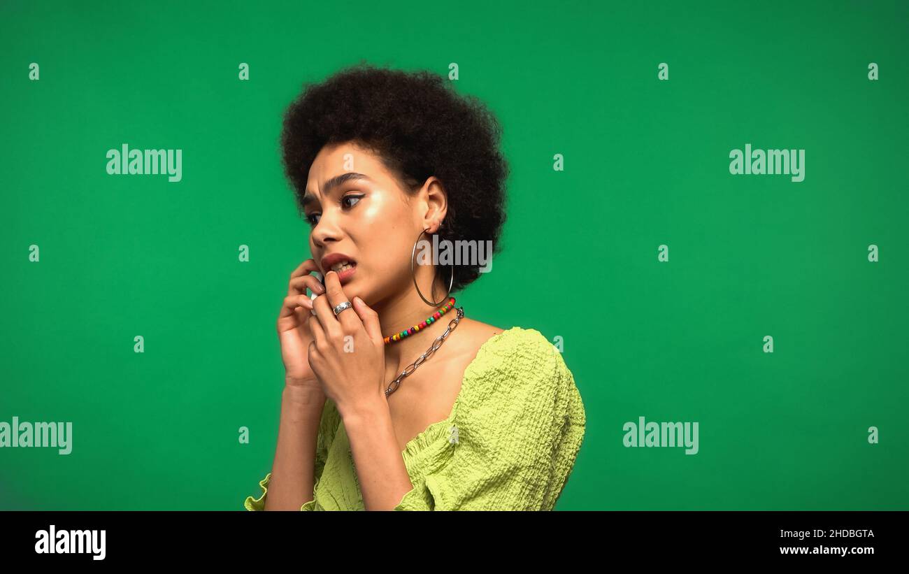 worried african american woman in blouse talking on cellphone isolated on green Stock Photo