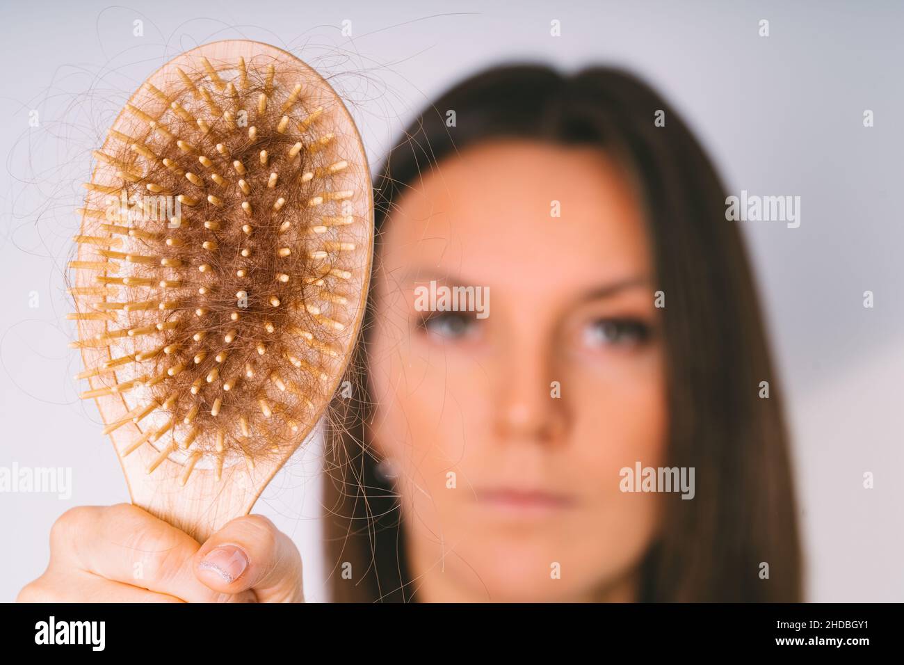 Woman showing hair brush with damaged hair. Hair loss problem. Bad hair