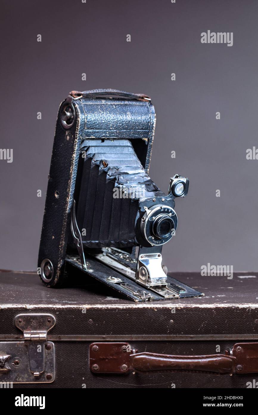 Old vintage camera lying on suitcase on gray background Stock Photo