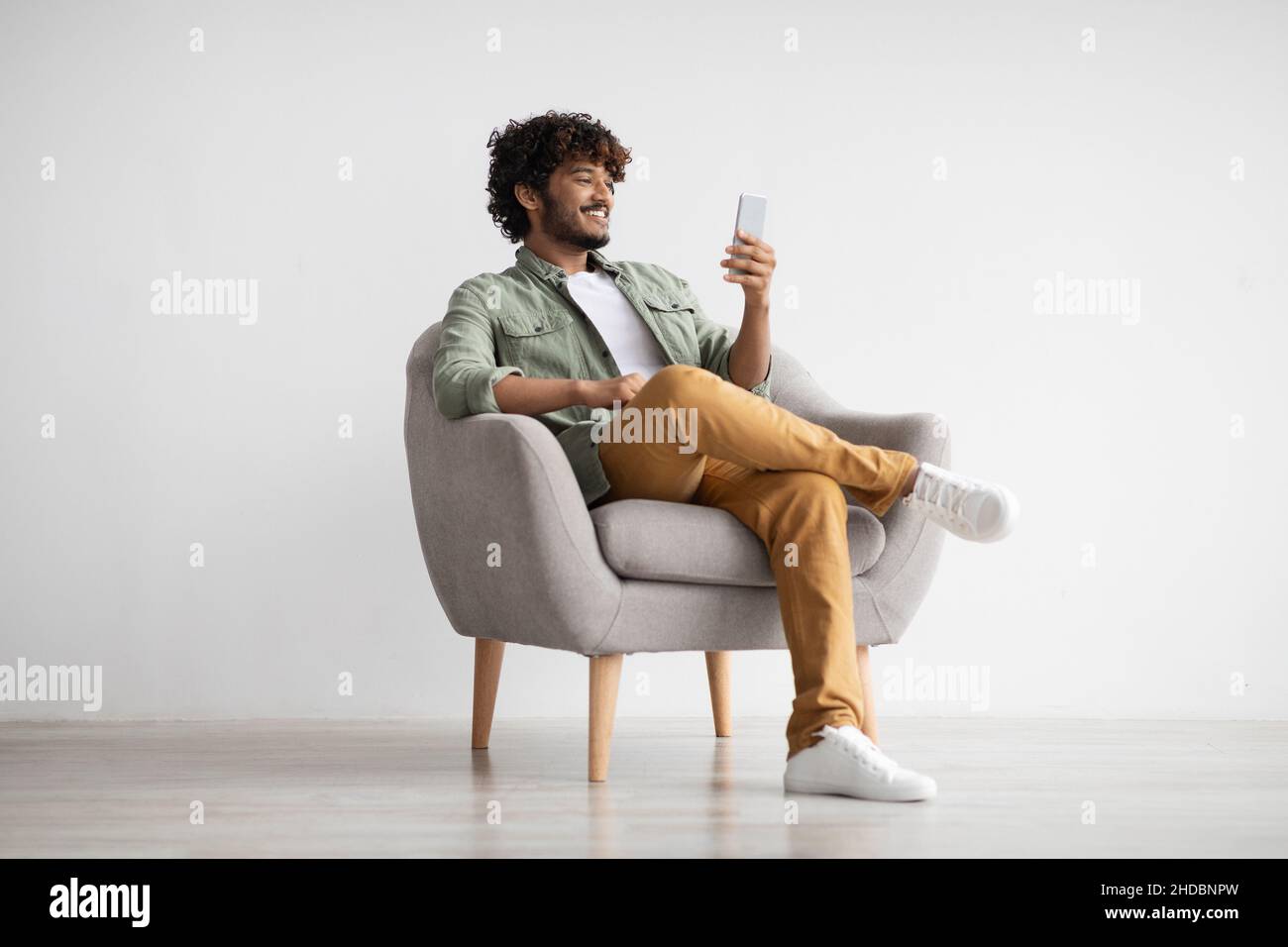 Cheerful young indian man chatting with girlfriend, using smartphone Stock Photo