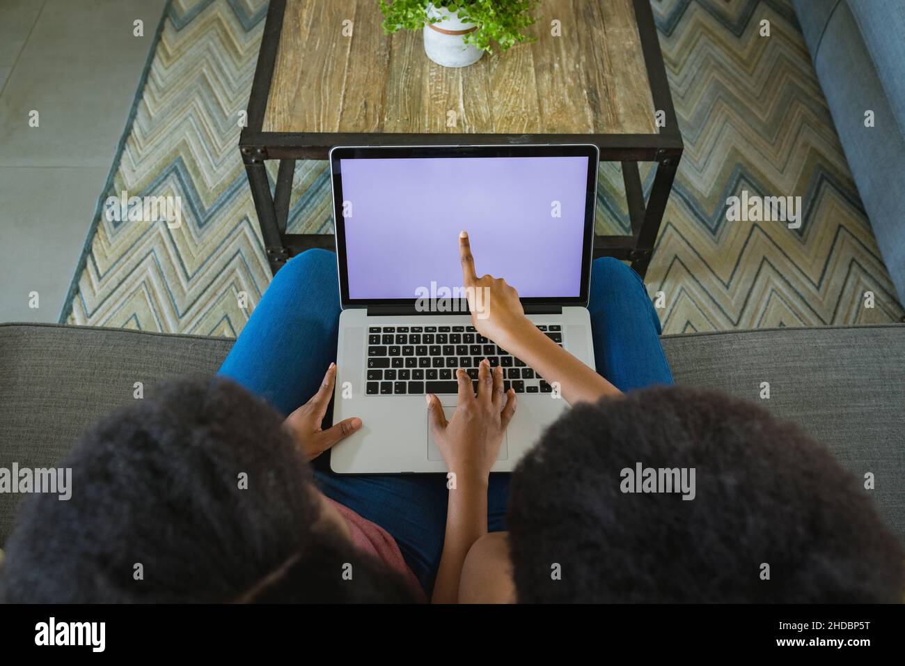 Teenage girl pointing at screen while teaching mother to use laptop at home, copy space Stock Photo