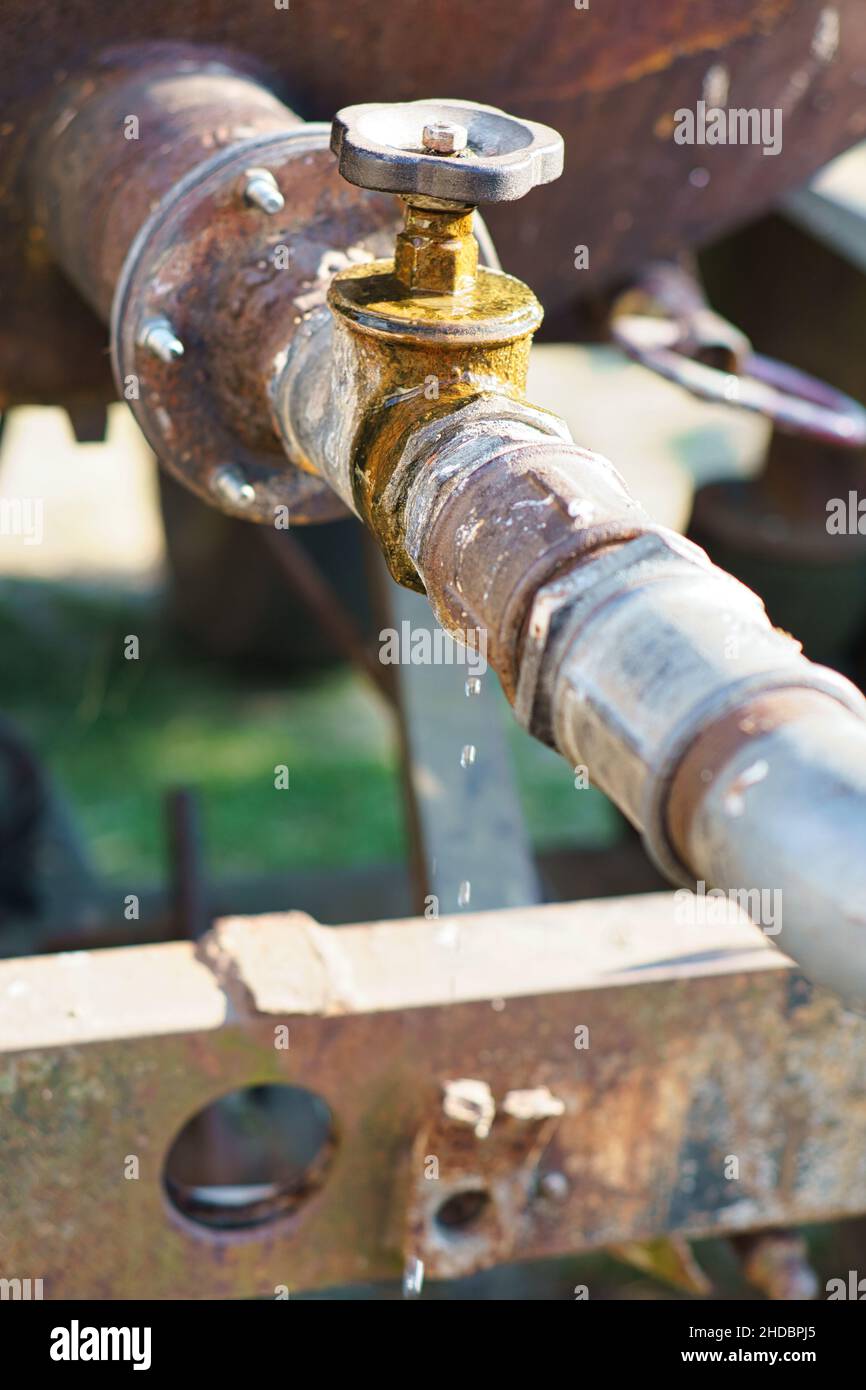 Dripping tap of a water tank in the open . Drops fall from the pipe