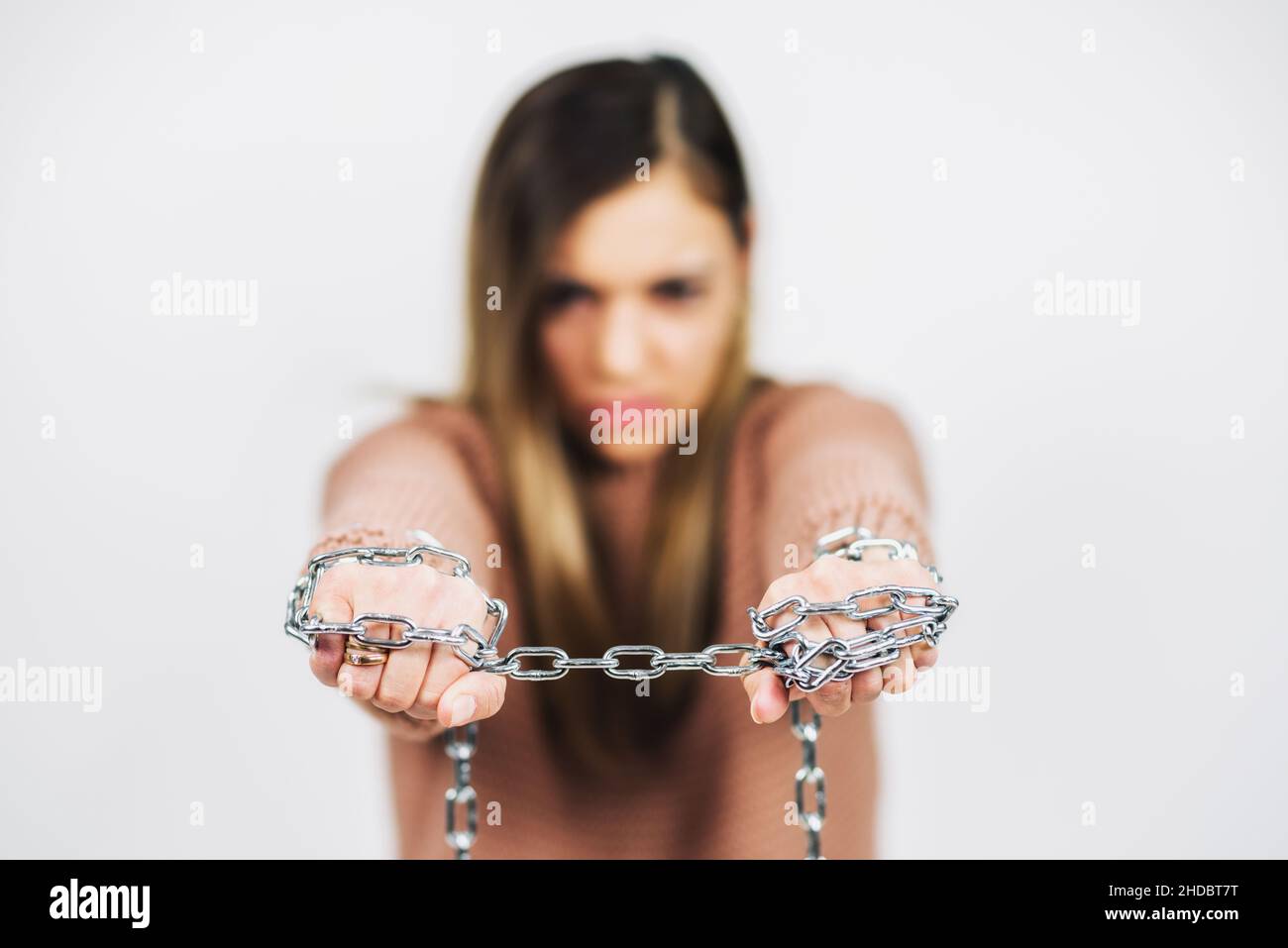 Hand of woman chained with iron chain on white background Stock Photo