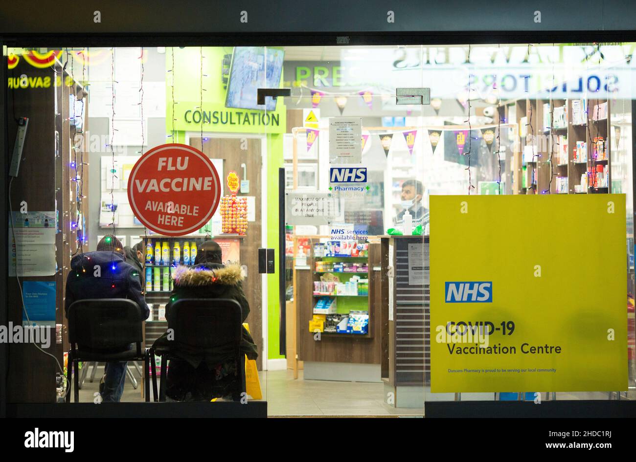 People are seen waiting inside a pharmacy where Covid-19 vaccines are offered on Christmas Day in London in the early morning. Stock Photo