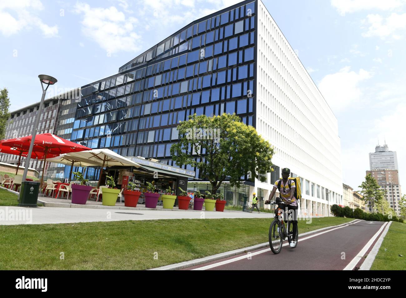 A delivery biker with modern glass buildings office at Porta Nuova, in Milan. Stock Photo