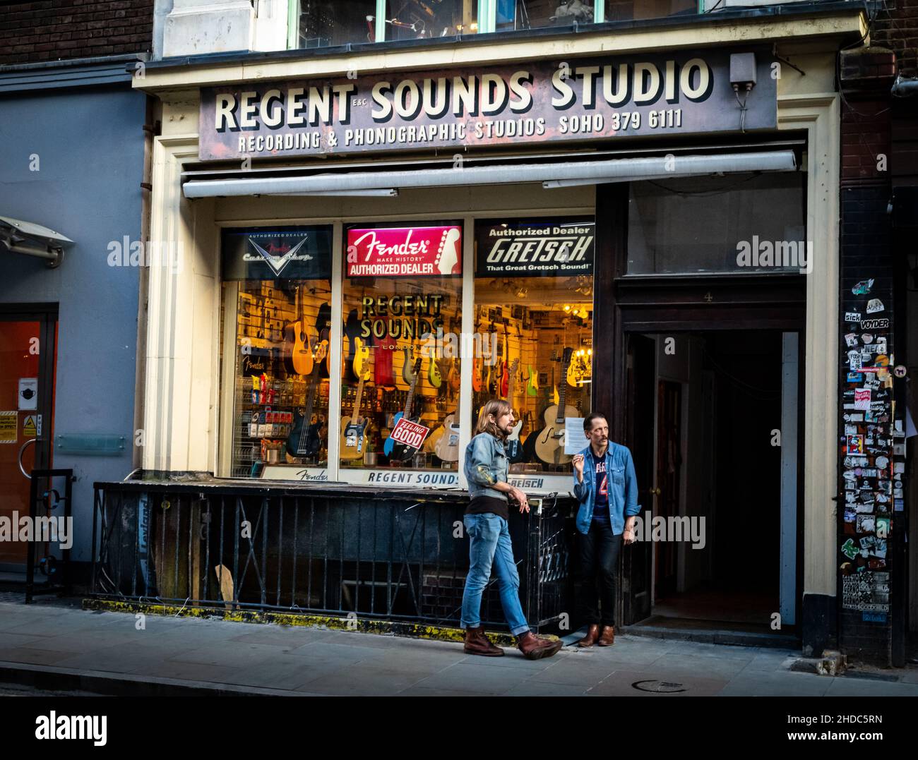 Two denim-clad rockers stand outside the famous music shop and recording studio Regent Sounds in Denmark St, London UK. Stock Photo