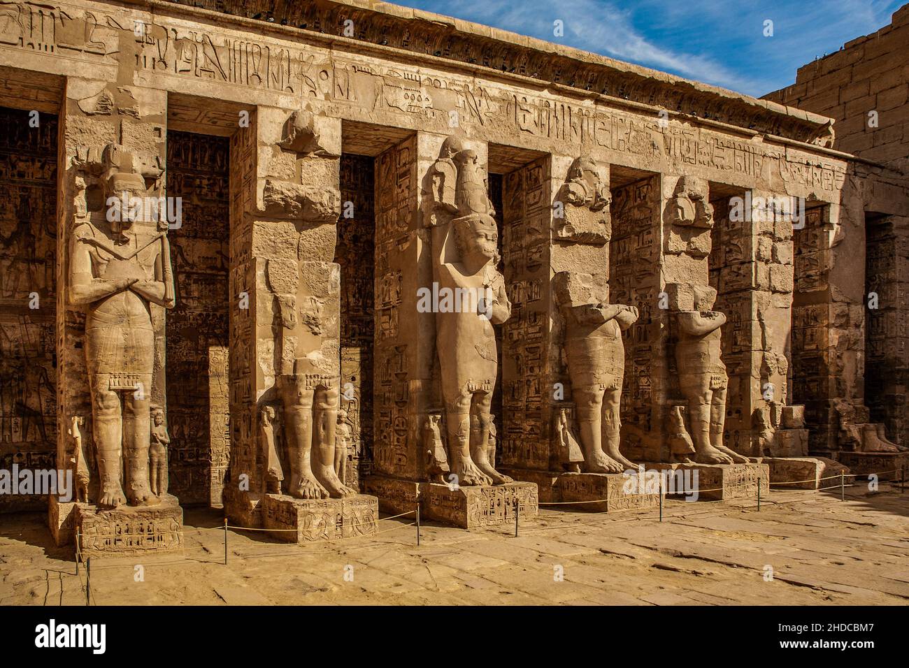 In the 1st courtyard, pillars with statues of Osiris hold up the ceiling of the walkway, Medinet Habu, mortuary temple of Ramses III. Luxor, Thebes-We Stock Photo