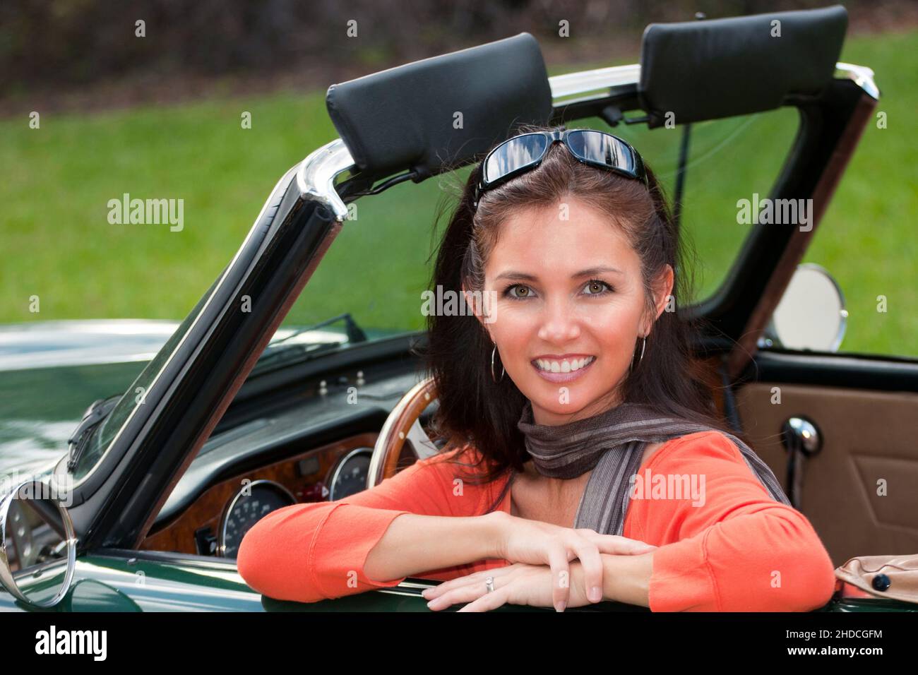 Junge Frau blickt entspannt aus einem Triumph TR6 Sportwagen Stock Photo