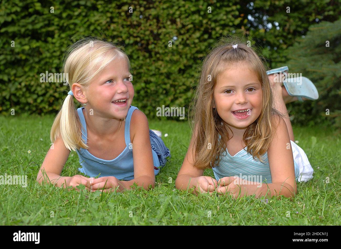 Zwei lachende Kinder liegen im Park auf einer Wiese, Mädchen, 6 Jahre, MR: Yes Stock Photo