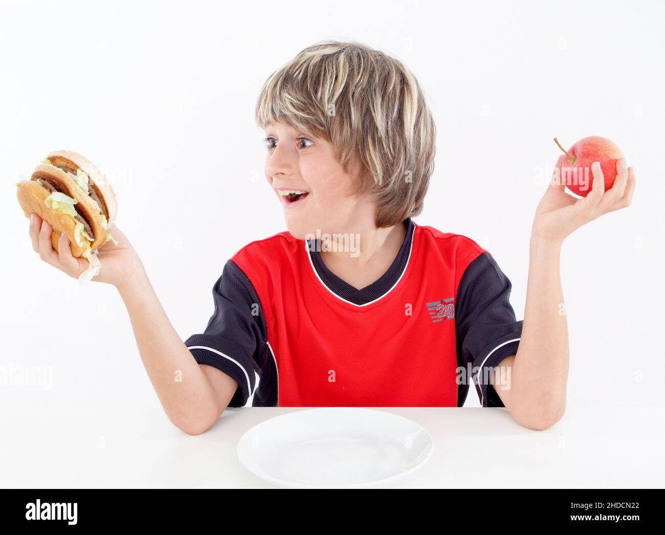 Junge mit Hamburger und Apfel, kann sich nicht entscheiden, Burger oder Apfel, Stock Photo
