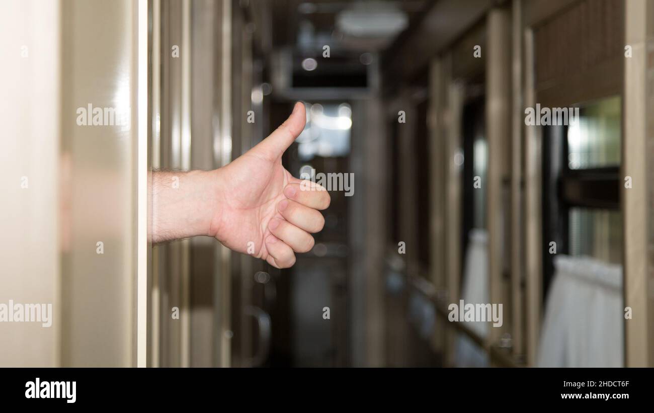 A man hand stuck out of the compartment car with his thumb raised up ...