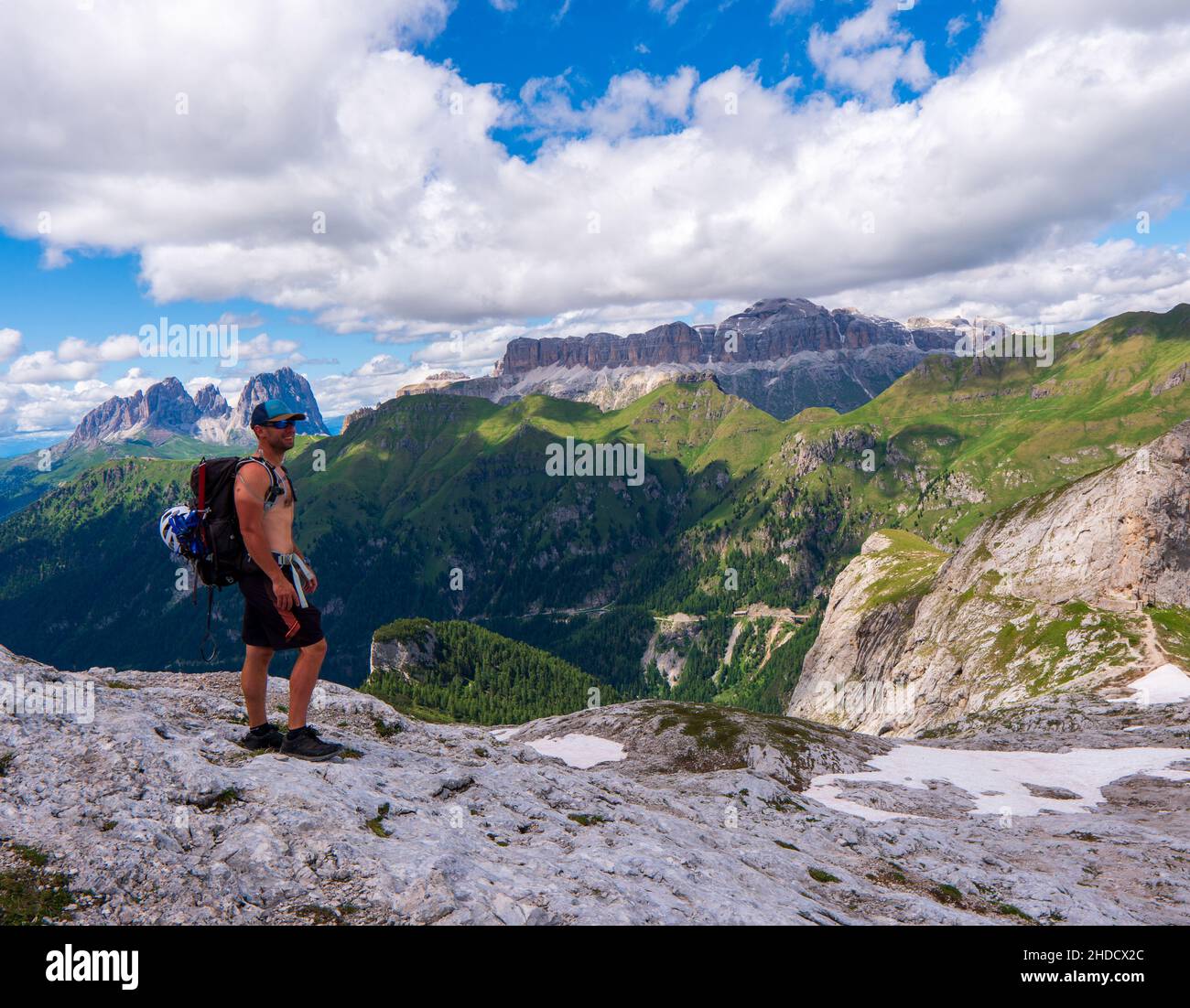 Hiking man adventure travel explorer hiker on mountain summit looking at landscape view. Hiker tramping up famous trail hike to marmolada dolomites. i Stock Photo