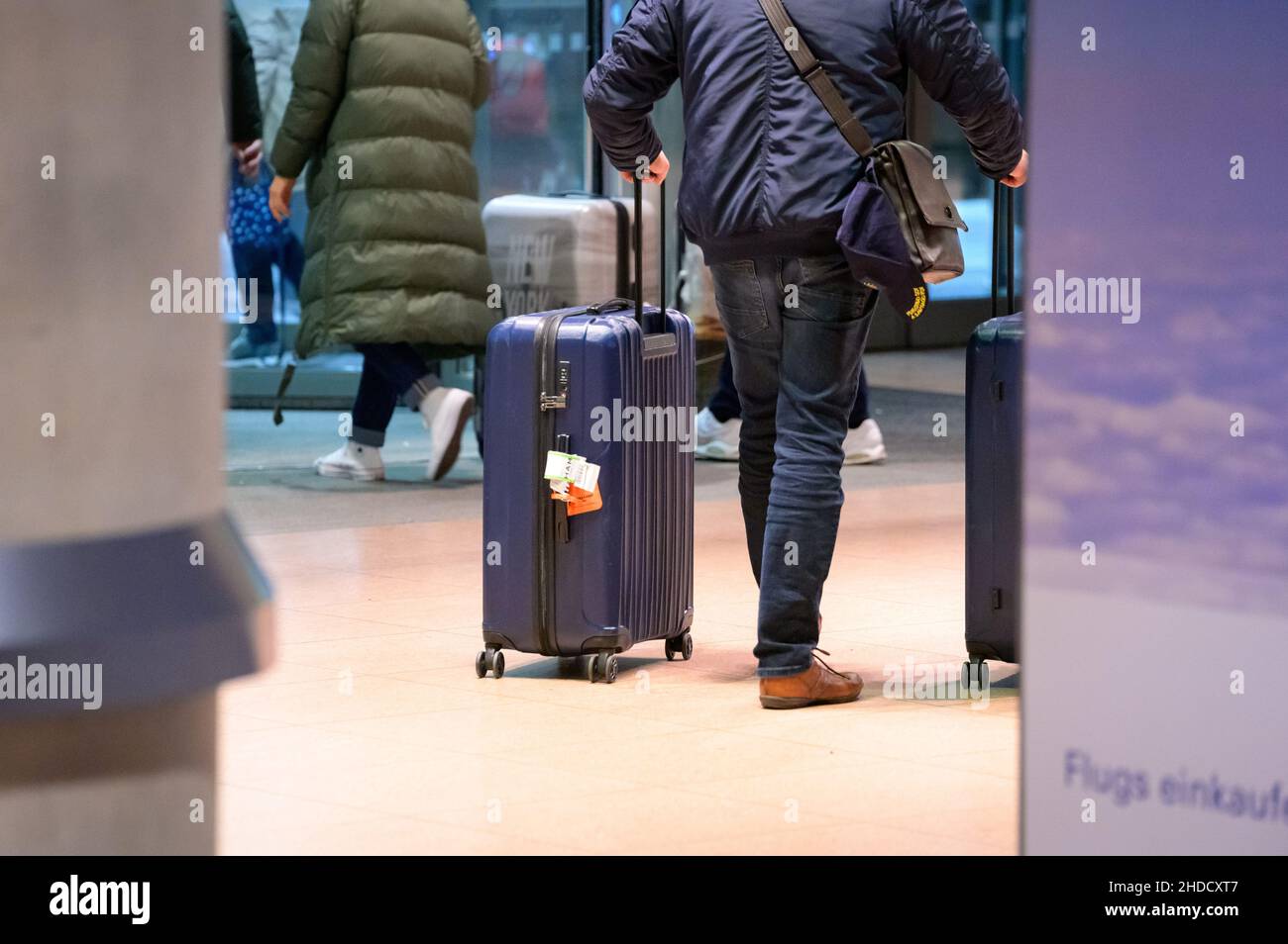 Hamburg, Germany. 04th Jan, 2022. Returning passengers of the cruise ship 'Aidanova' walk through the arrivals area of Hamburg airport with their suitcases during the night after being flown back to Germany in one of two charter flights. Aida Cruises had decided to cancel the voyage of the 'Aidanova' in Lisbon after the cases of infection and not to continue towards the Canary Islands until Wednesday as planned. Credit: Jonas Walzberg/dpa/Alamy Live News Stock Photo