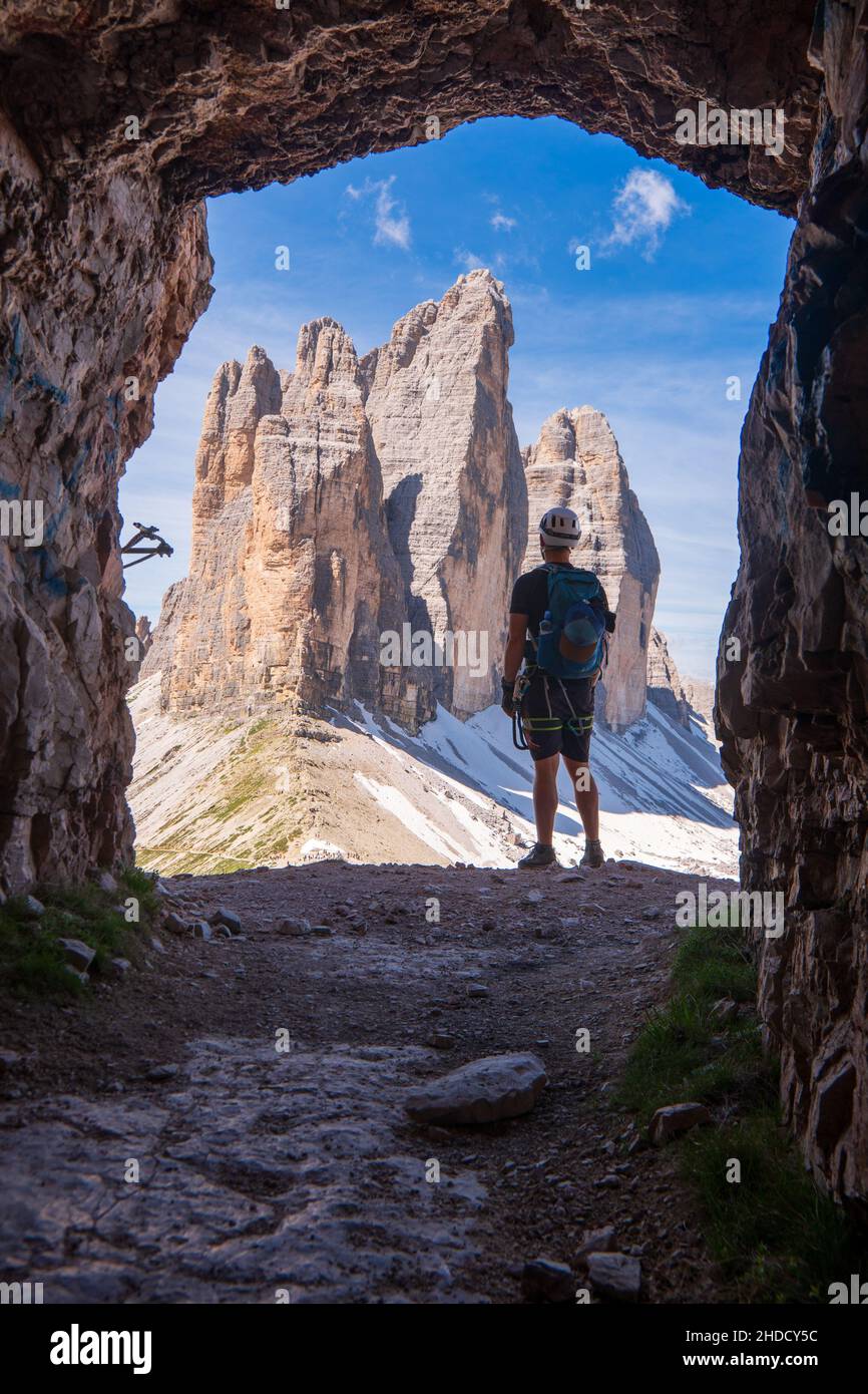 Tourist with hiking backpacks in mountain hike on summer day. Tourist in beautiful mountain landscape. Young guy go along the footpath through the mou Stock Photo
