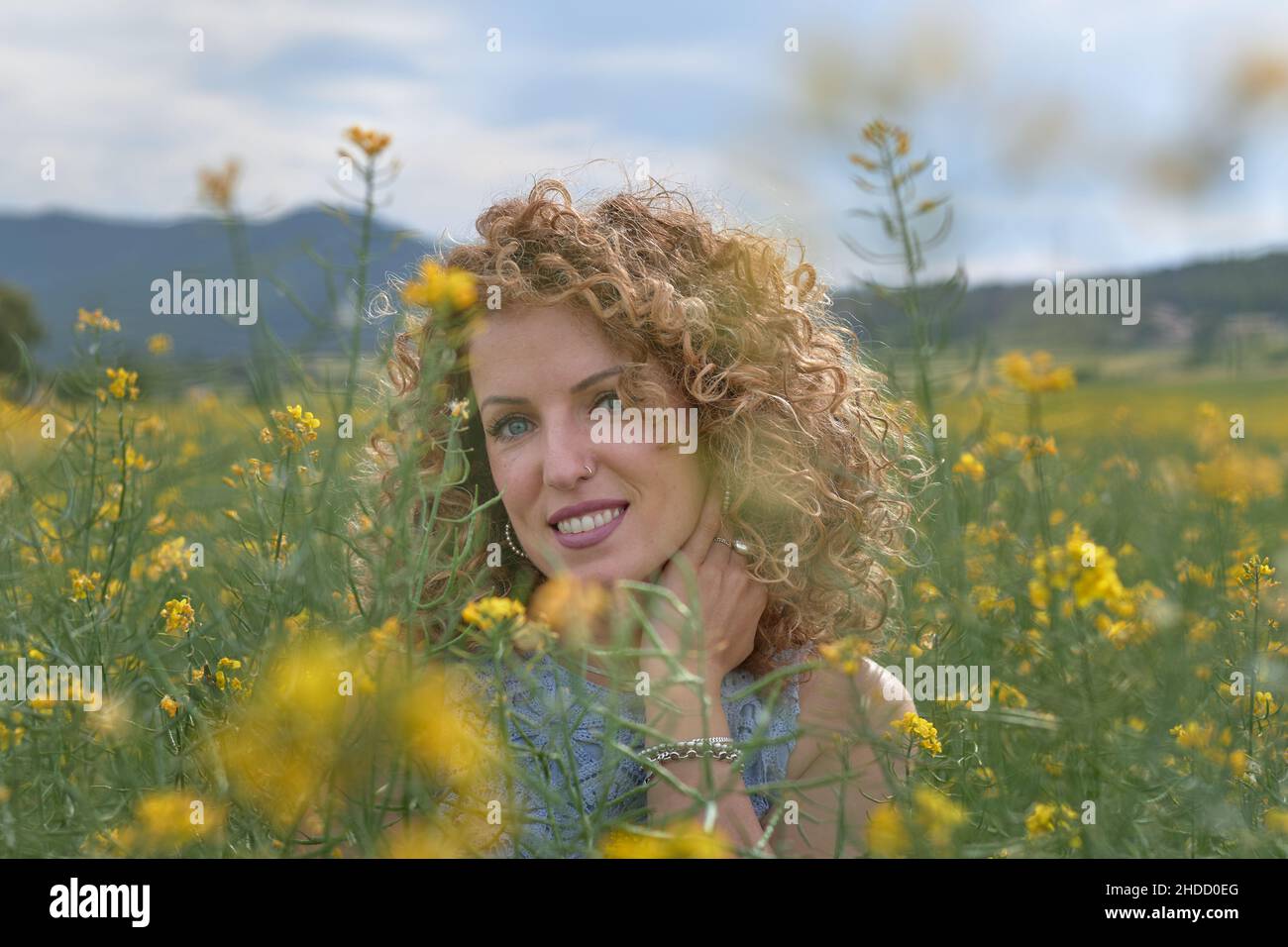 Beautiful young woman with curly hair in a flower field. Flower in hair