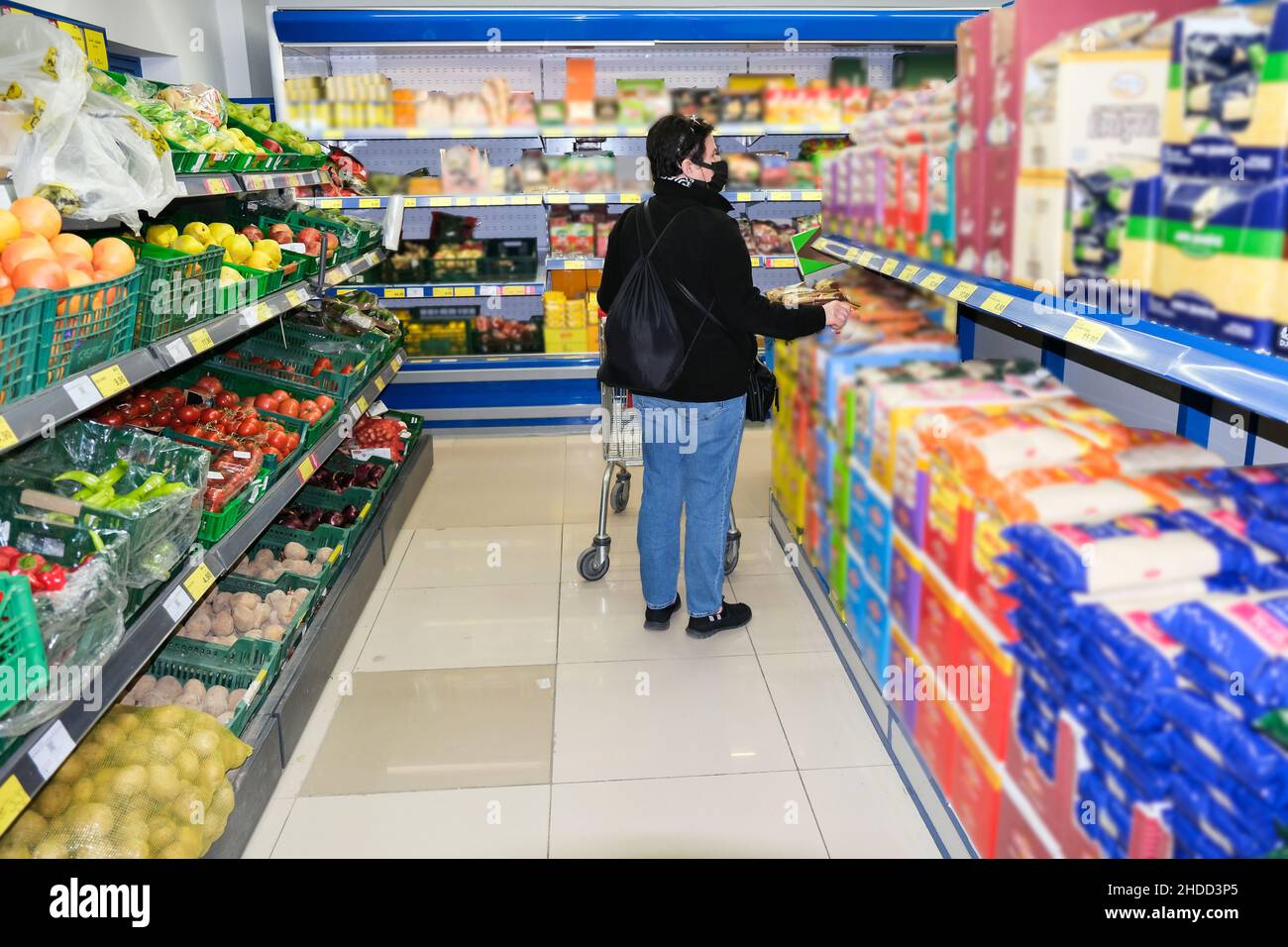 Antalya, Turkey - January 04 2022: Blurry image, a women with face mask overlooks produce in a grocery store and checking the price of food products. Stock Photo