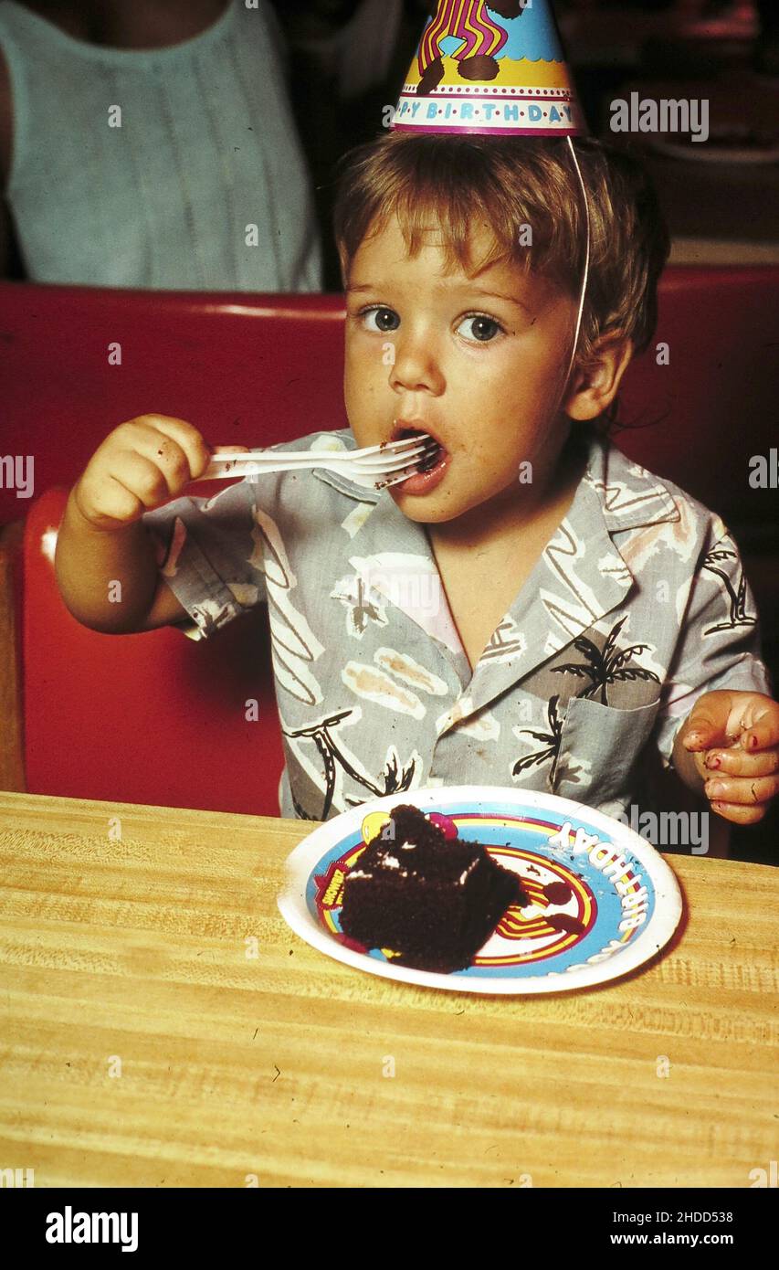 Austin Texas USA, 1989 Child using fork to eat chocolate cake during