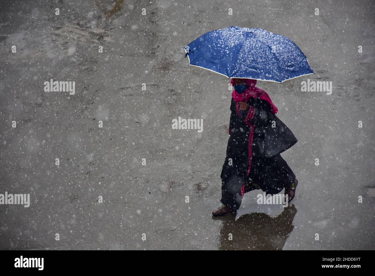 A woman shelters underneath an umbrella during a snowfall in Srinagar. Kashmir has recorded widespread light to moderate rain and snow,  leading to cancellation flights to and from Srinagar ‘international’ airport while several far-flung areas remained cut off on Wednesday. The Meteorological department said that they are expecting a 'heavy snowfall' on the 7th-8th of this month. Stock Photo