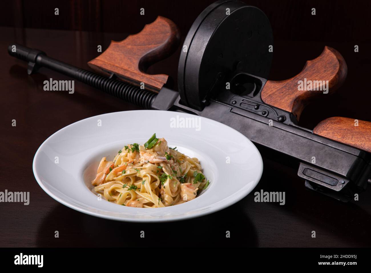 Thompson submachine gun and Italian pasta with prawns chili pepper and greens Stock Photo