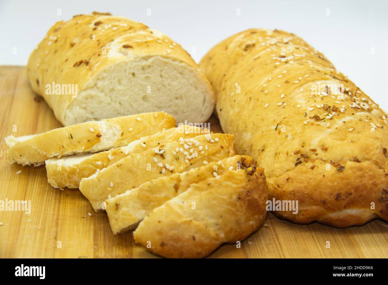 Wheat bread baked from flour at home. Sliced bread on wooden board  against background. Food with NO GMO. Homemade bread with spice on it. Stock Photo
