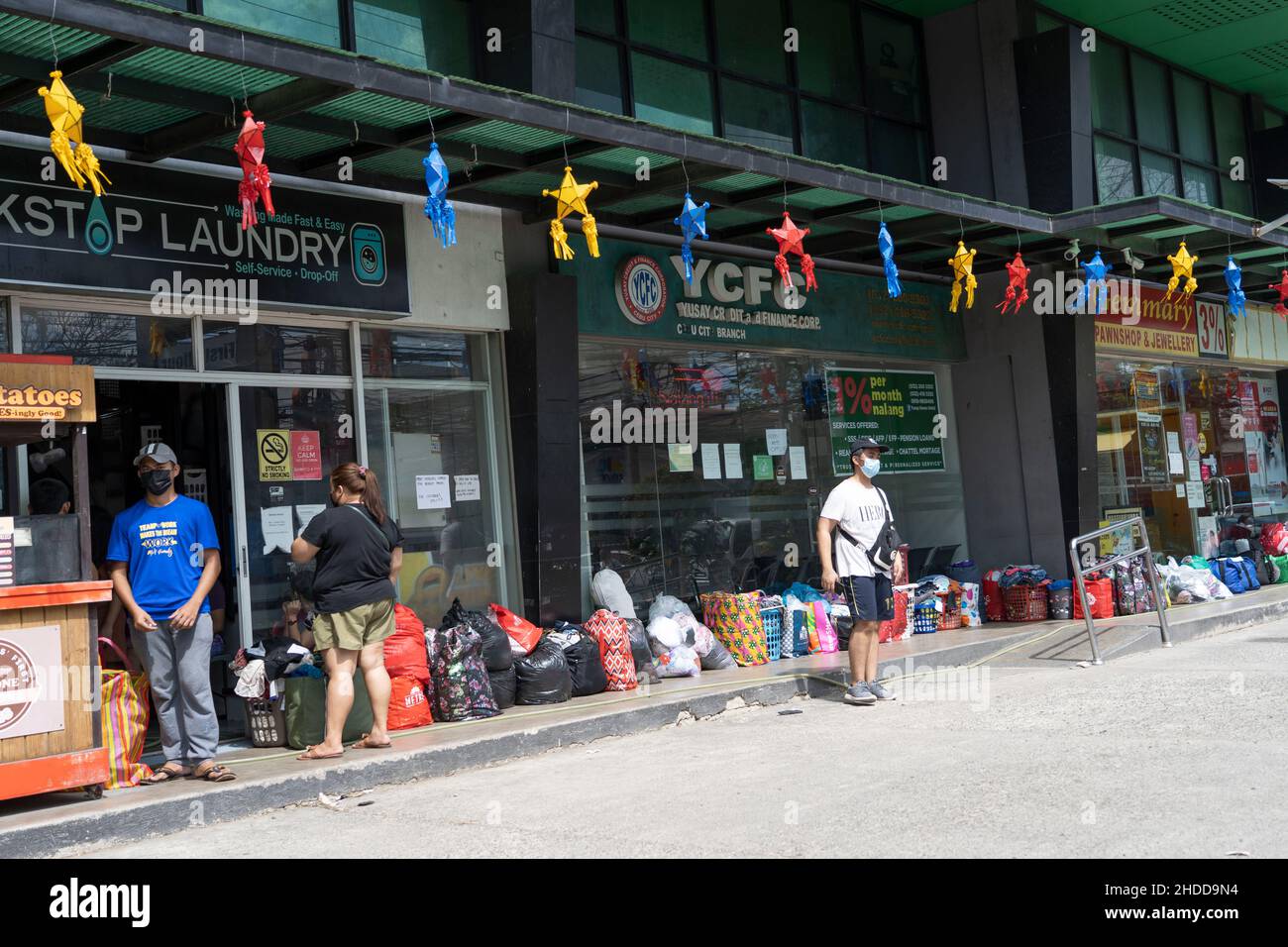 Lines of laundry bags in a line as people wait to was their clothes after Typhoon Odette struck the Philippines on 16th December 2021 Stock Photo