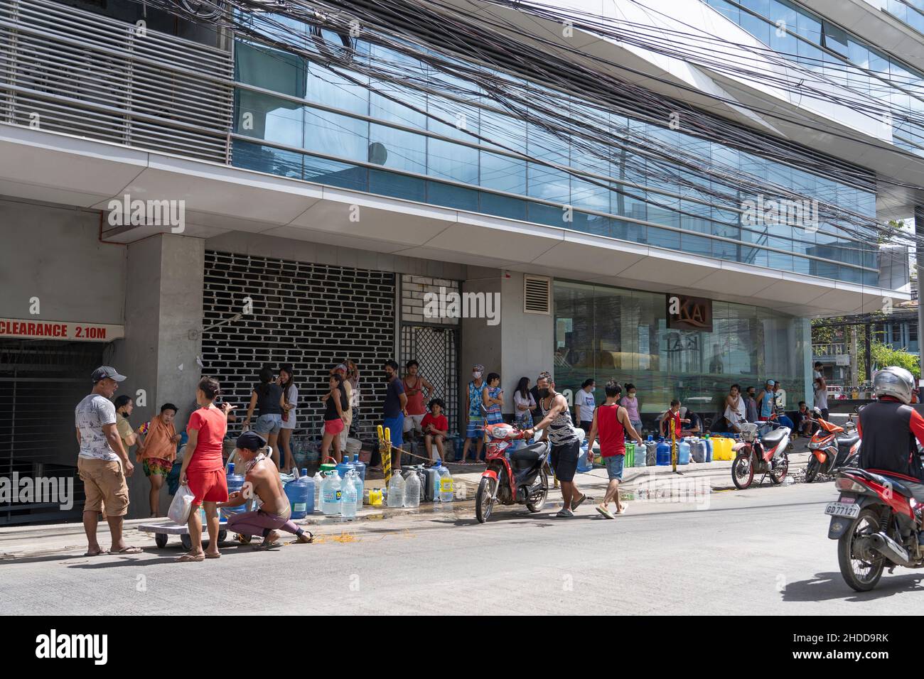 People queueing for fresh drinking water from a Hotel in the aftermath of Typhoon Odette which struck the Philippines on 16th December 2021 Stock Photo