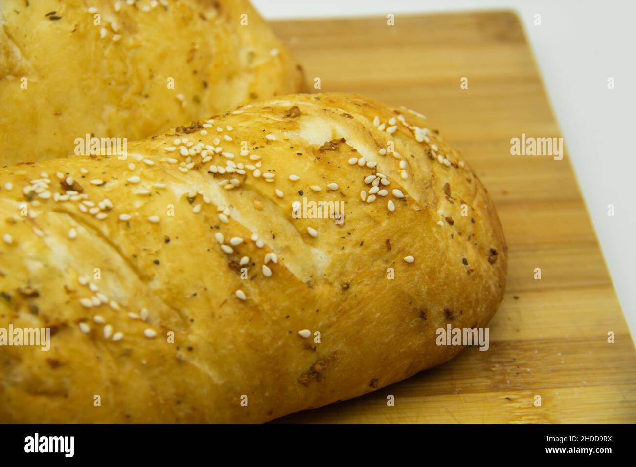 Wheat bread baked from flour at home. Tasty bread on wooden board  against background. Food with NO GMO. Homemade bread with spice on it. Stock Photo