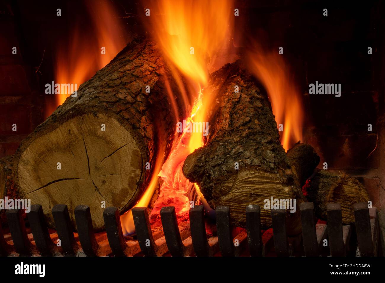Burning logs inside the fireplace, giving warm atmosphere and coziness. Stock Photo