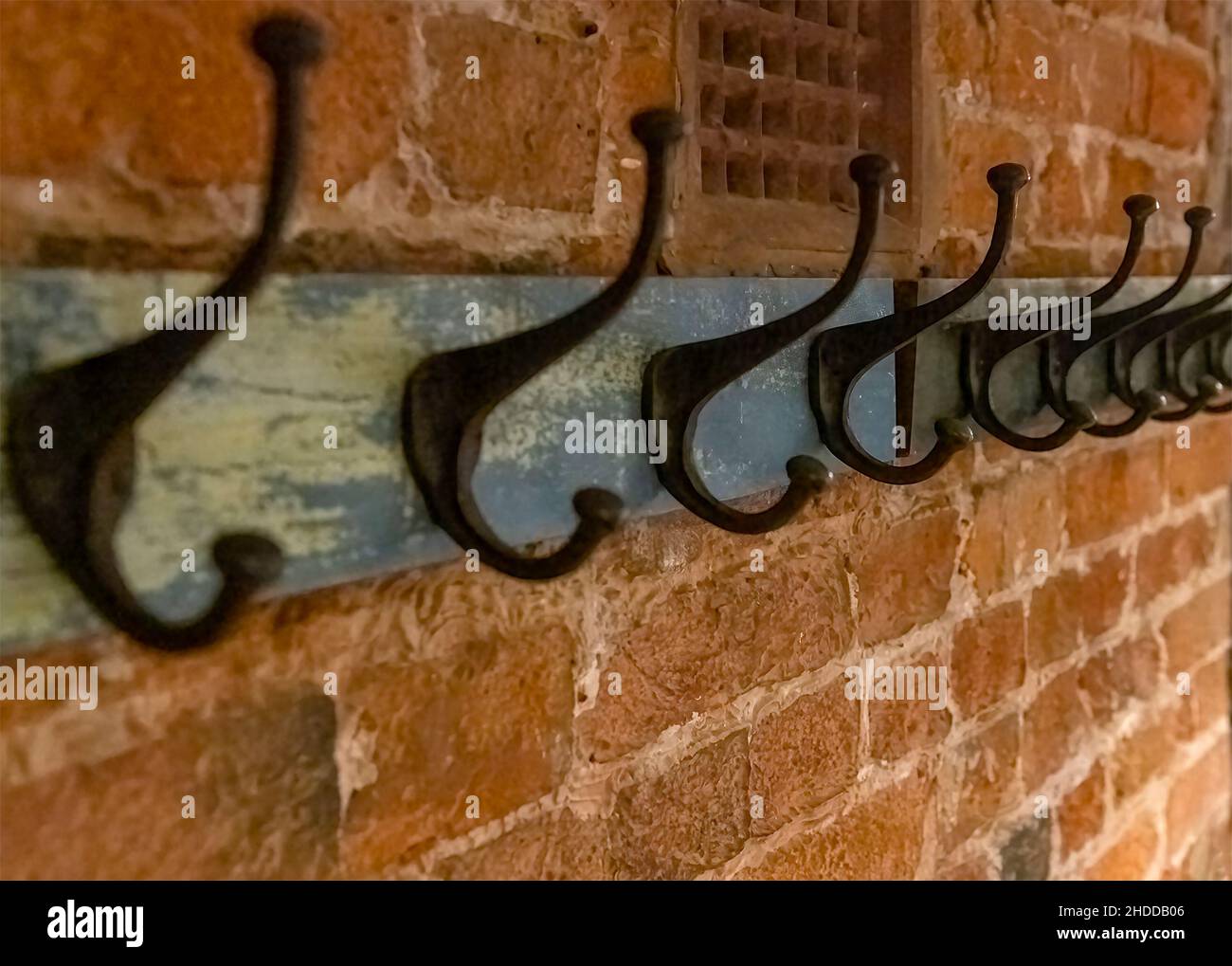 Wrought iron coat hangers place on old vintage wood hung on a brick textured wall with a blank leftside for copy space shot in selective focus with a Stock Photo