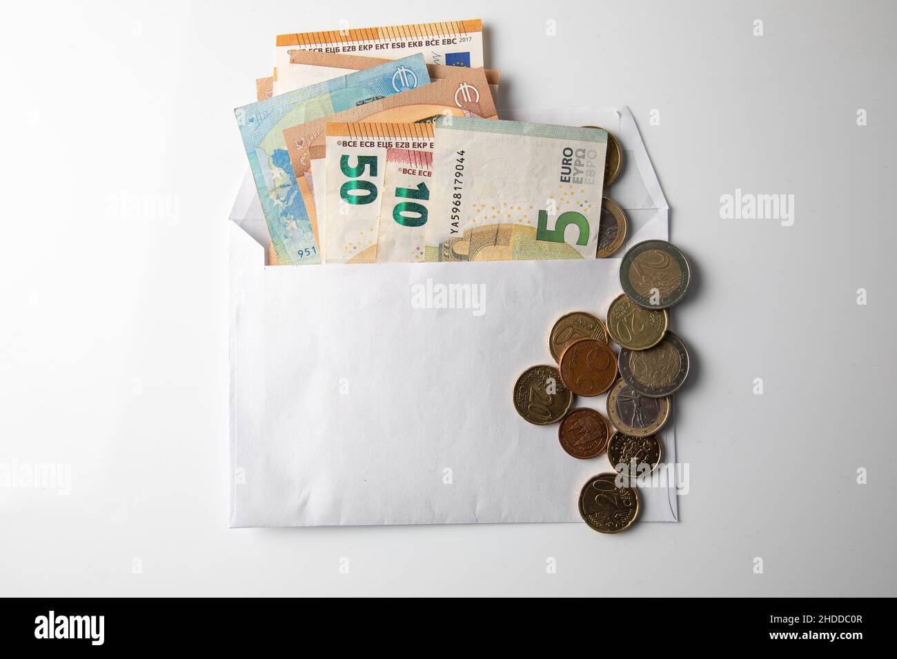 wad of cash in a white envelope on white background Stock Photo