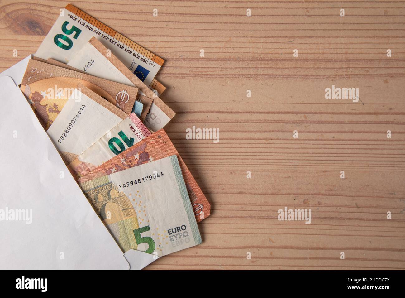 wad of cash in a white envelope on wooden table Stock Photo