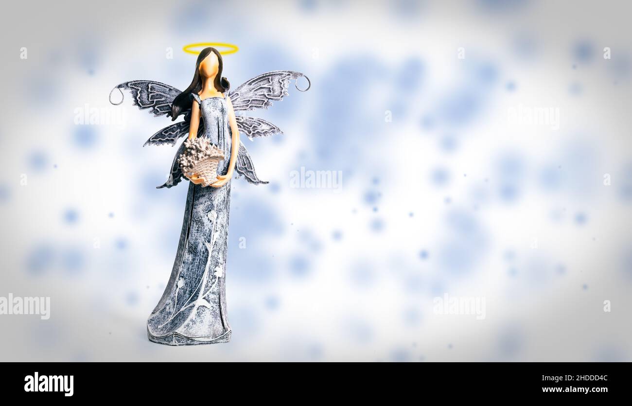 Angel with halo on blue and white background. Statue of angel. Spiritual, faith, heaven. Guardian Angel with copy space. Stock Photo