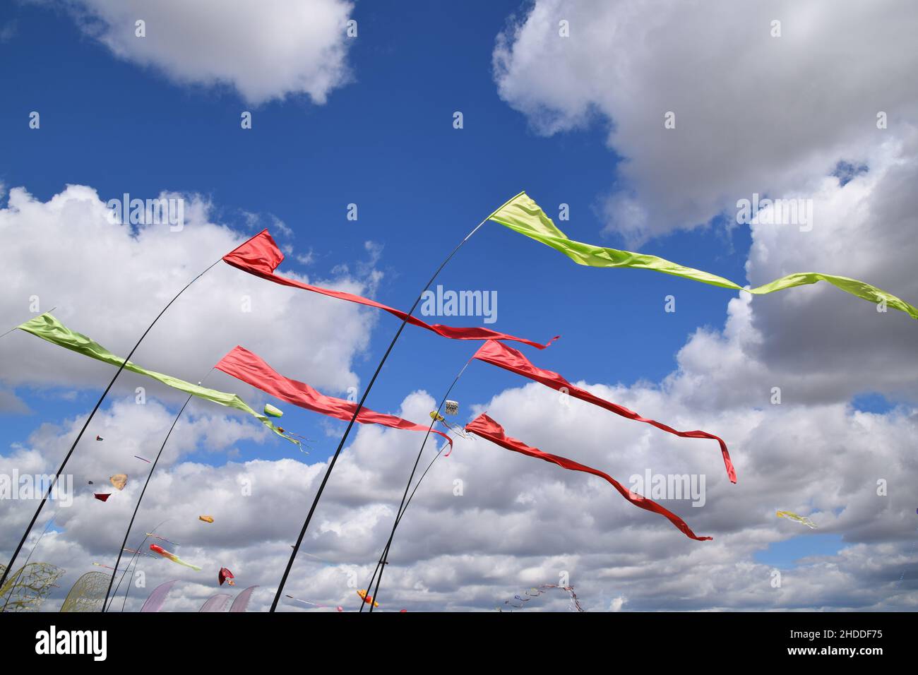 Looking up at colourful thin flags on a windy day Stock Photo