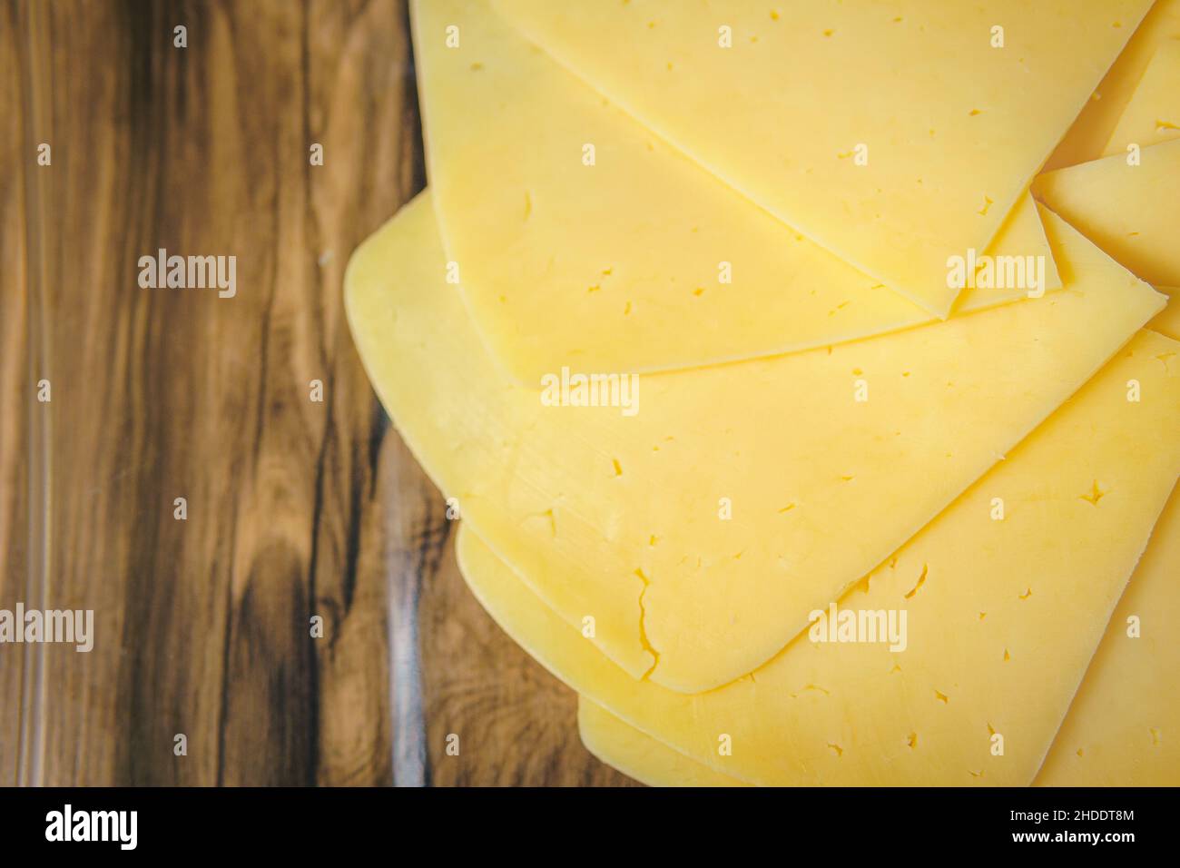 On the table are slices of yellow cheese, approaching a cheese plate