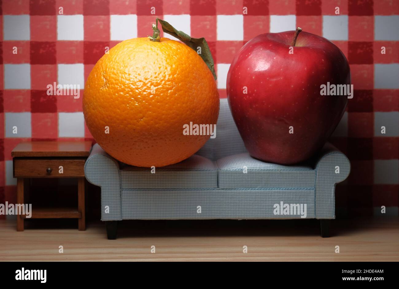 Comparing apples to oranges idiom concept with fruit sitting on sofa Stock Photo