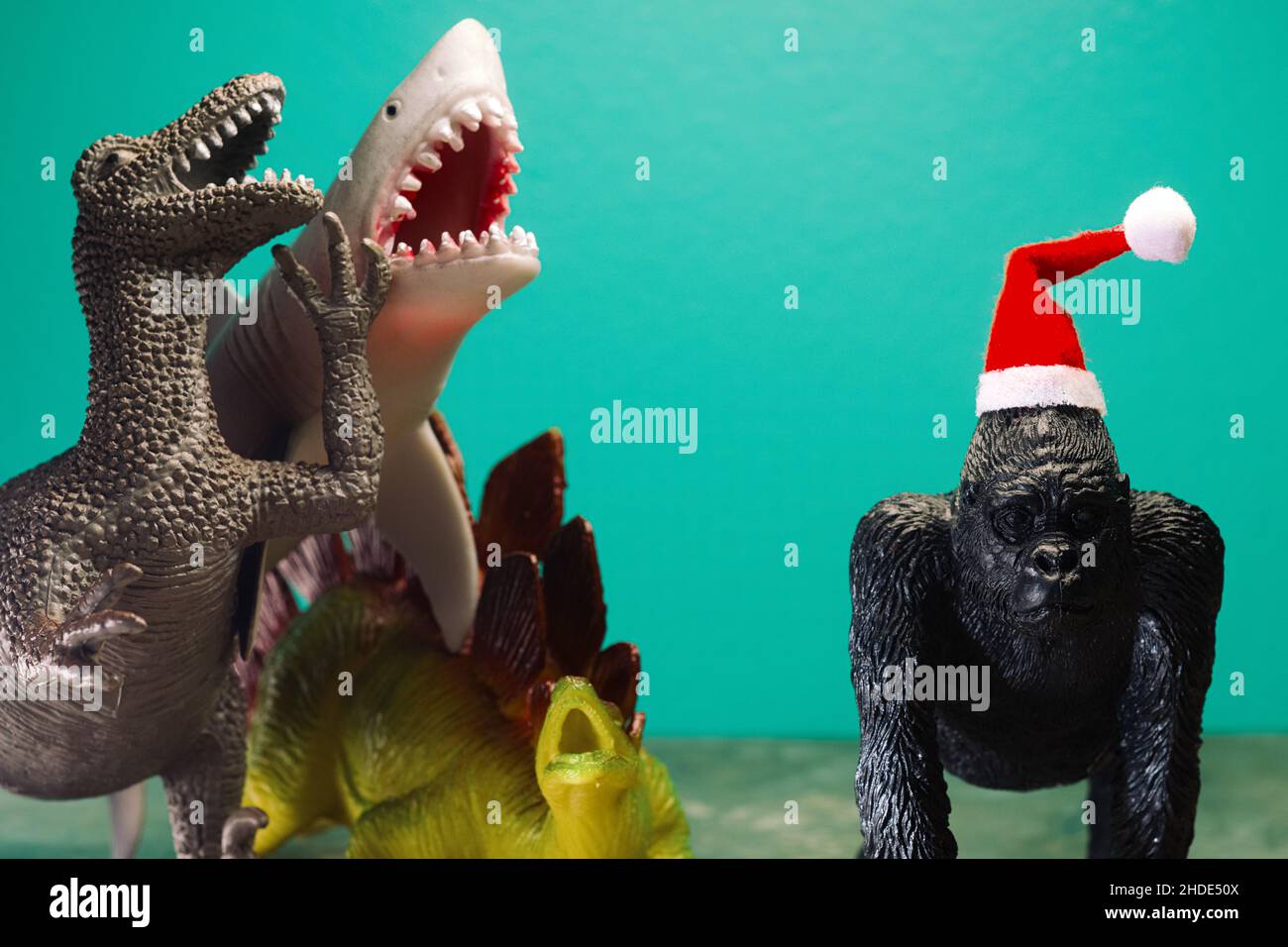 Uninvited for Christmas hysterical laughing bullies mock sad gorilla wearing santa hat as metaphor Stock Photo
