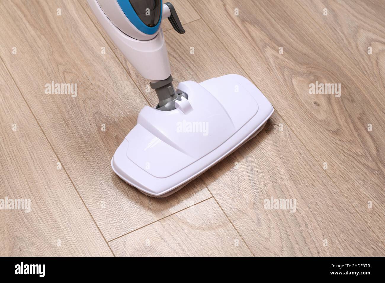 A man washes laminate flooring with a steam mop. Killing germs, clean floor, decontamination