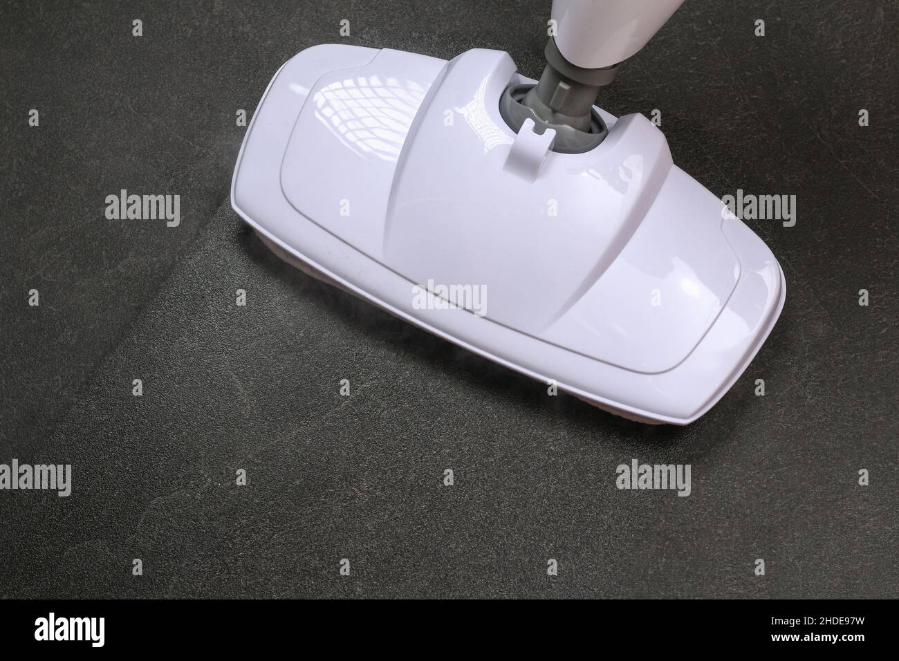 A man washes black porcelain stoneware with a steam mop. Killing germs