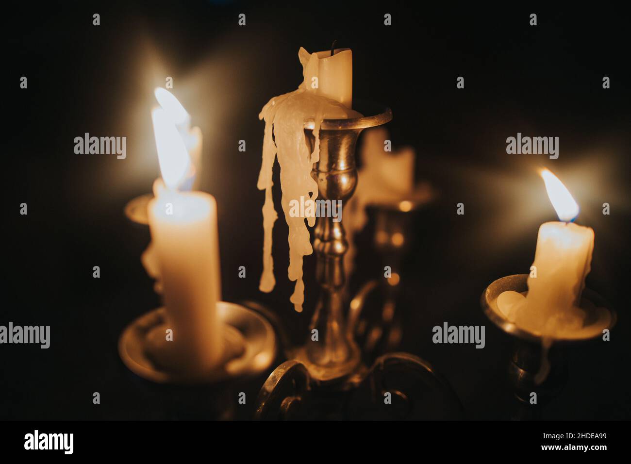 Burning candles on an old brass candlestick against a black background