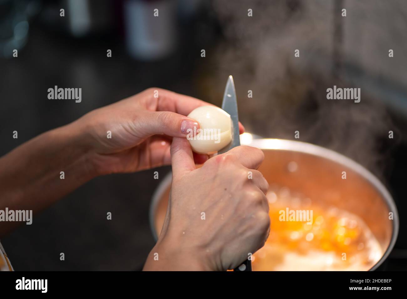 Woman's hands cut an onion with a knife in half Stock Photo - Alamy