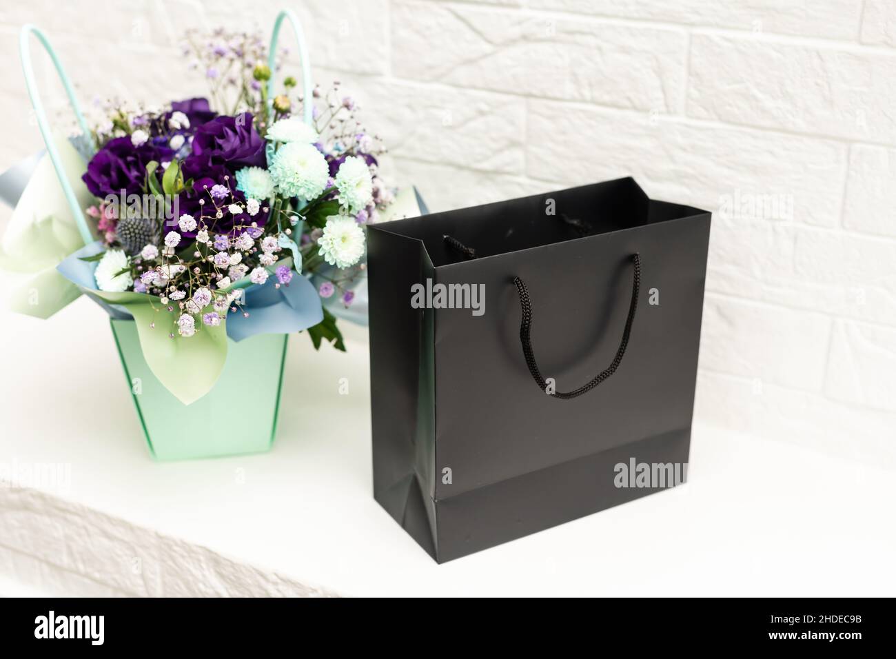 black empty paper bags and bouquets. Blank wall Stock Photo