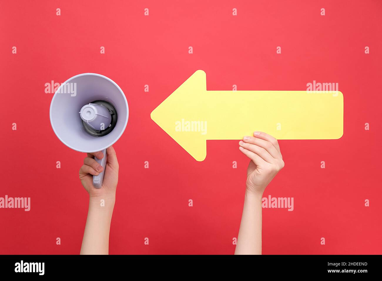 Close up of female hand holding megaphone pointing on big yellow arrow ...