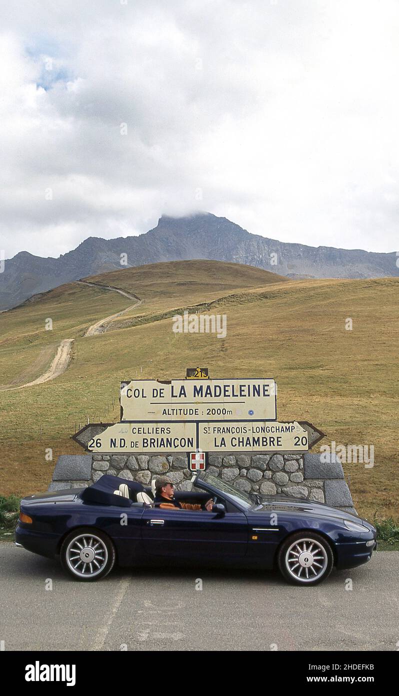 Road trip along Route Des Grandes Alpes. Driving the Col De La Madeleine, France in a 1996 Aston Martin DB7 Volante. Stock Photo
