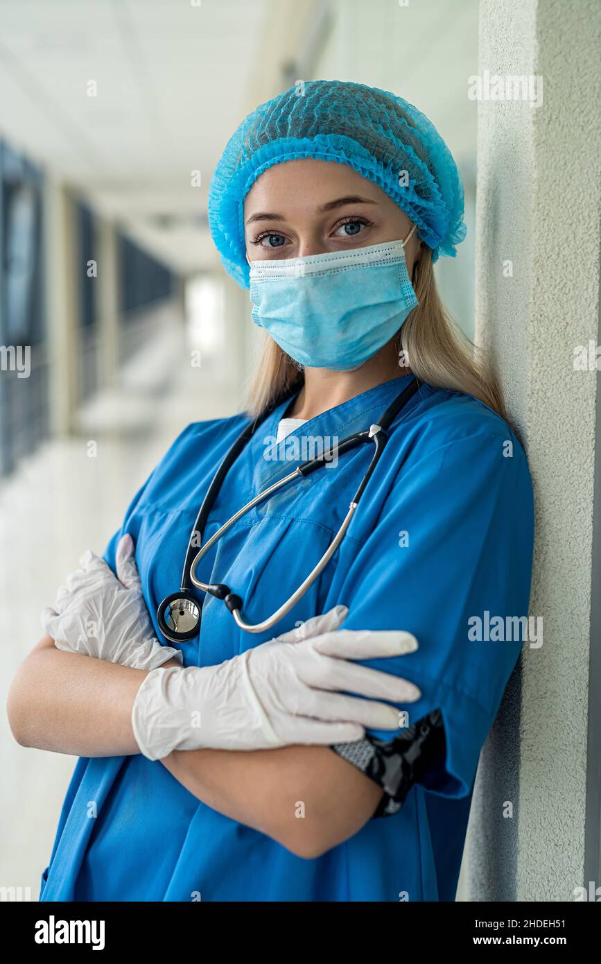 young nurse in uniform mask with mittens with stethoscope stands in hospital. Medicine concept Stock Photo