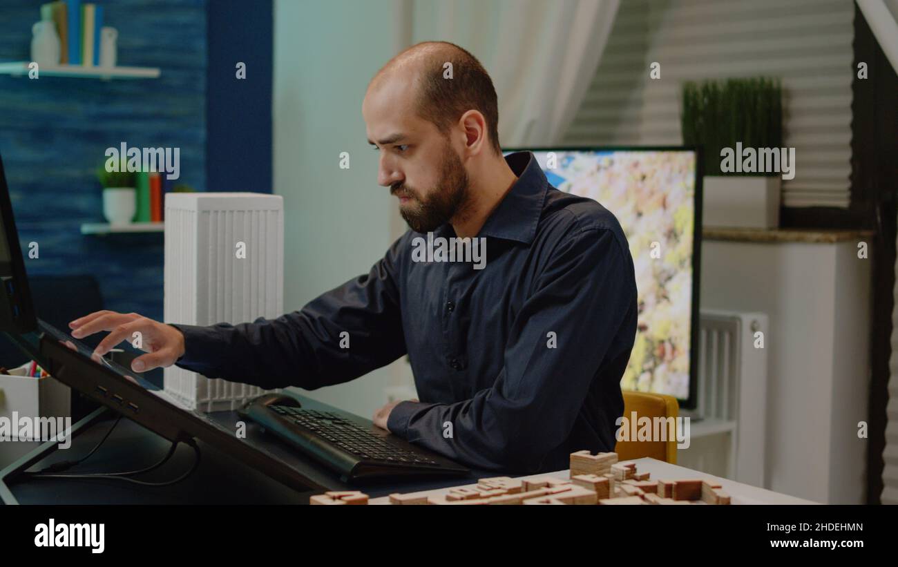 Man architect working on touch screen computer with building model for ...