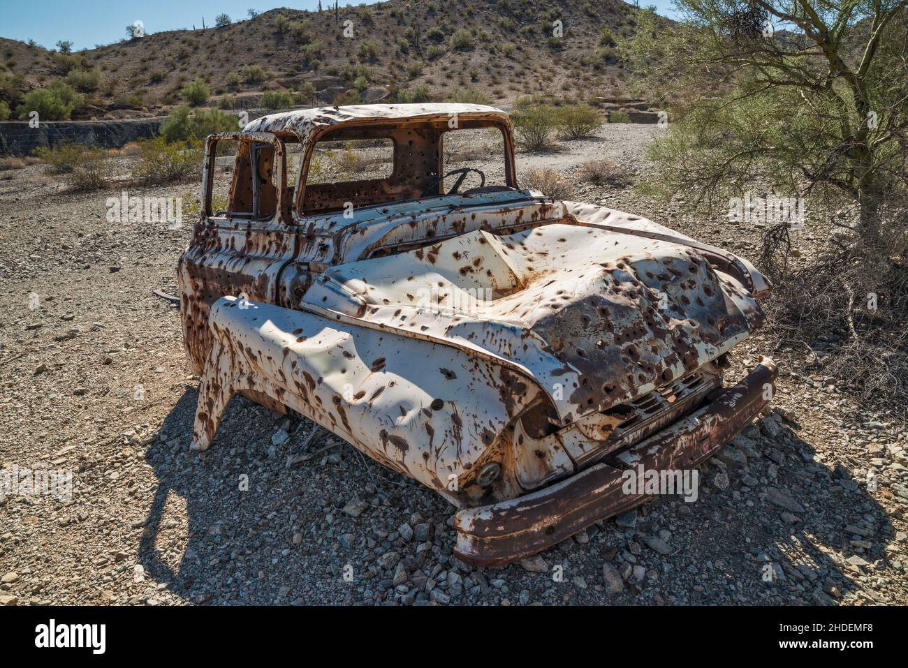 Old pick up truck wreck, riddled with bullet holes, at Swansea copper mining townsite, Buckskin Mountains, Sonoran Desert, Arizona, USA Stock Photo