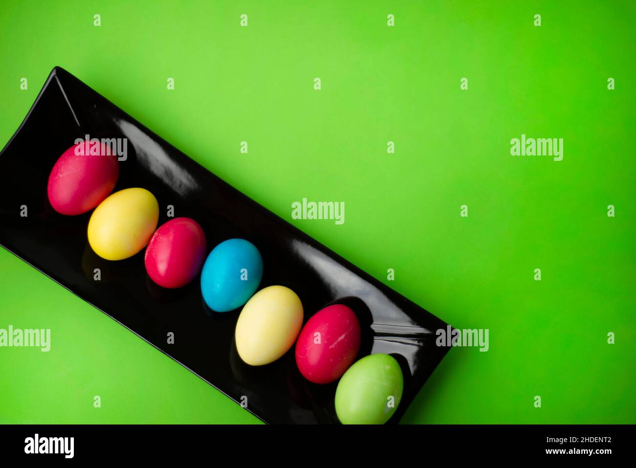Easter eggs on a rectangular black ceramic dish. Green background. Copy space for text. Stock Photo