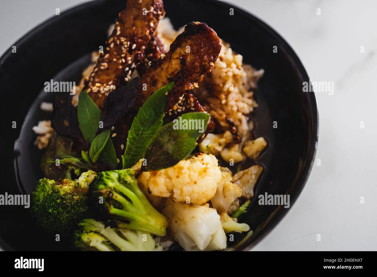 vegan marinated teriyaki tempeh withsteamed broccoli and coauliflower